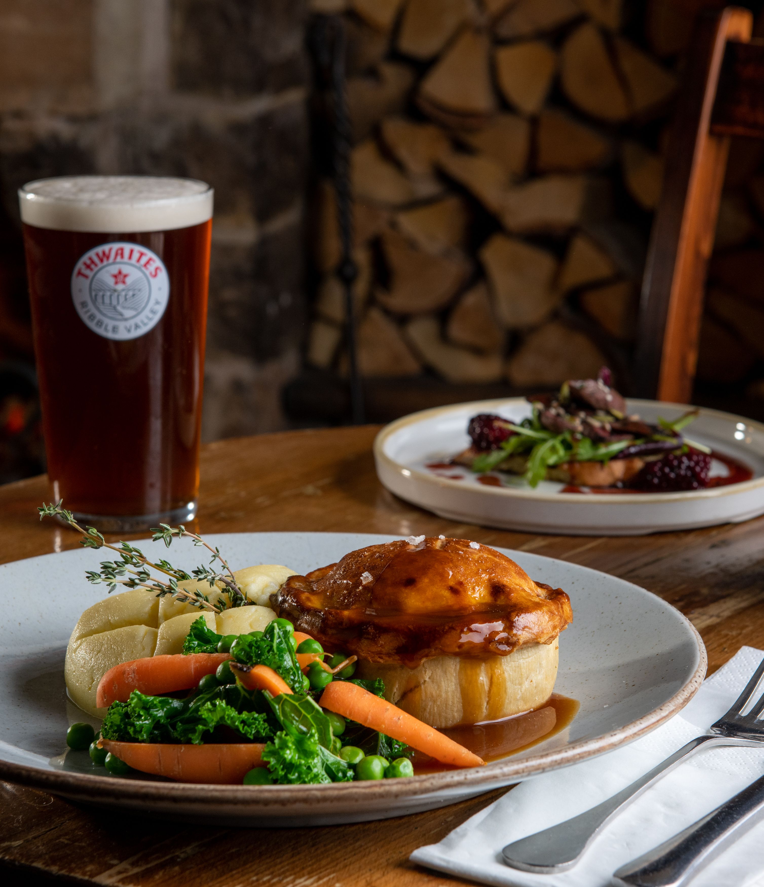 Pie, mash, vegetables and gravy on a plate with a pint of thwaites ale