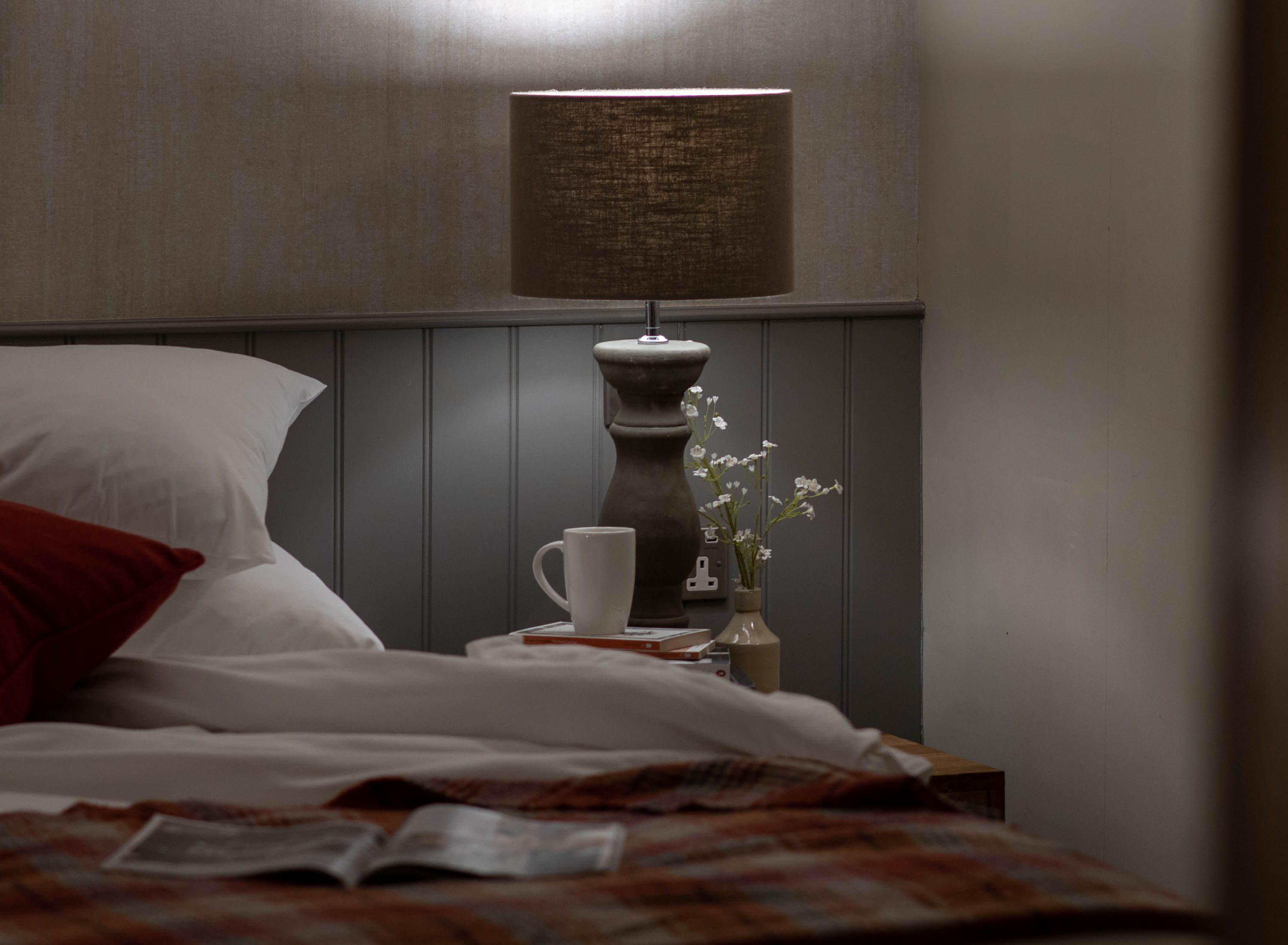 Cosy bed with open magazine and bedside table with coffee