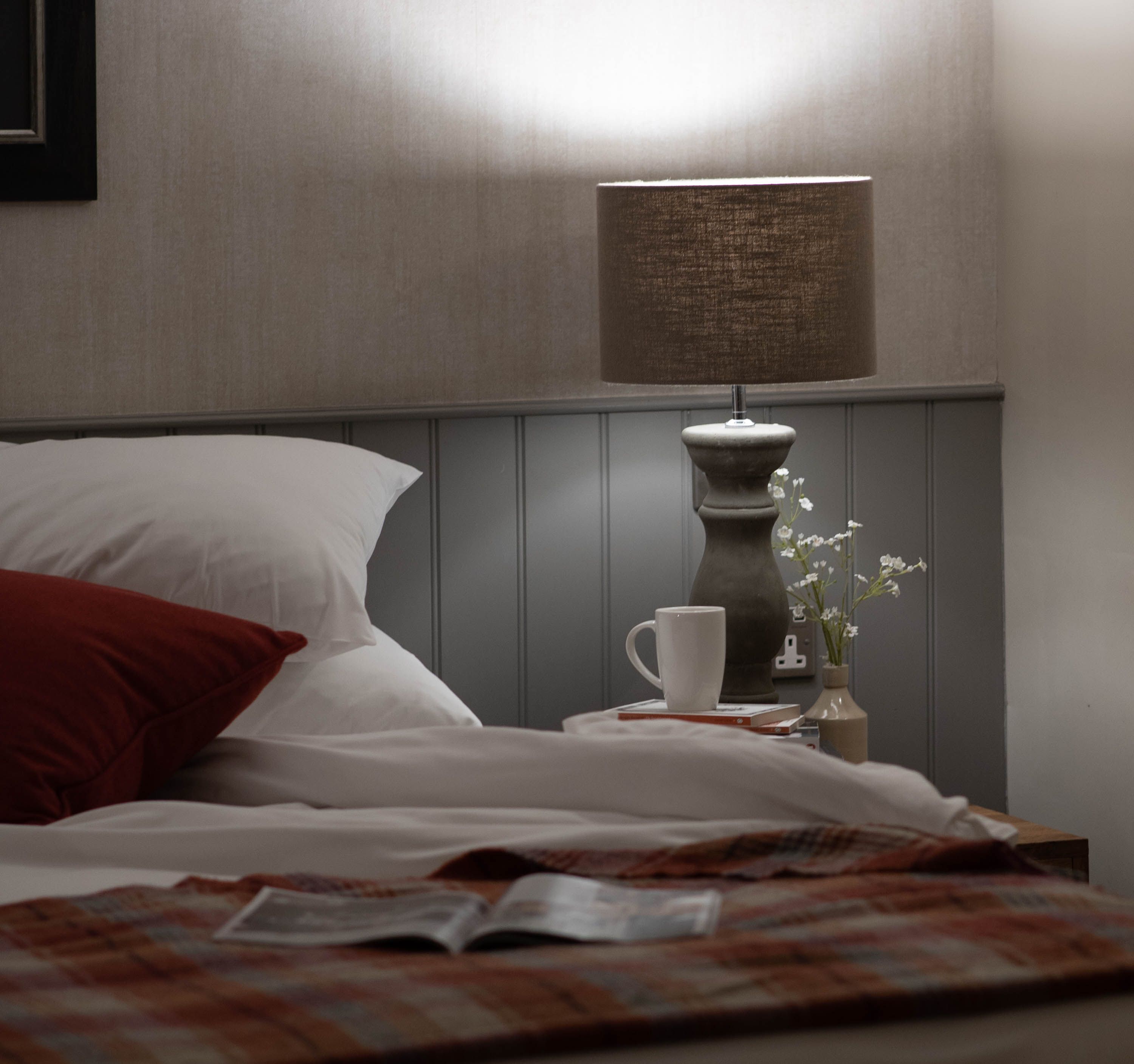 Cosy bed with open magazine and bedside table with coffee